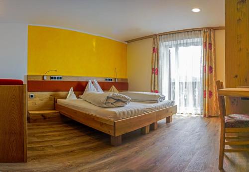 ein Schlafzimmer mit einem Bett und einer gelben Wand in der Unterkunft Drei Birken in Oberbozen