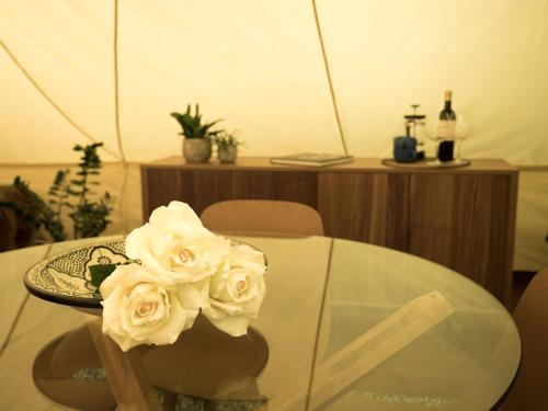 a glass table with a plate and flowers on it at Camp Boutique in Gaulverjabær