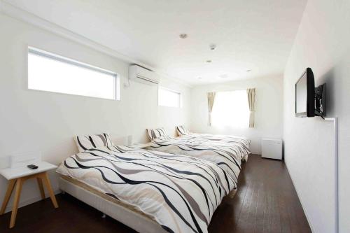 a white bedroom with a large bed with striped sheets at Shima Stay holoholo in Zamami