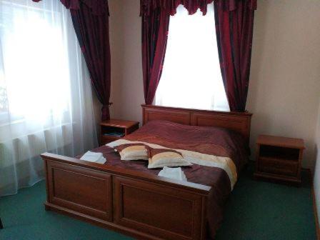 a bedroom with a wooden bed with two windows at Hotel Mirage in Sudovaya Vishnya