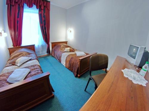 a hotel room with two beds and a wooden table at Hotel Mirage in Sudovaya Vishnya