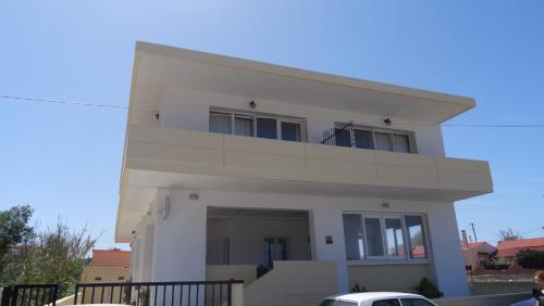 a white house with a balcony on top of it at Cathrin Beach Apartments in Stavros