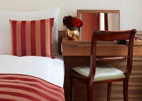 a bedroom with a desk with a bed and a chair at Living Hotel an der Oper in Vienna