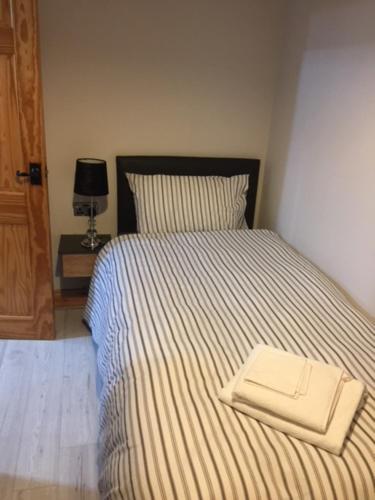 a bedroom with a bed with a striped blanket and a lamp at Dark Hedges Cottage in Ballycastle