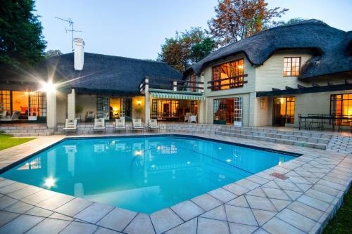 a swimming pool in front of a house at Thatchfoord Lodge in Johannesburg