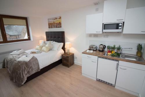 a small bedroom with a bed and a kitchen at Trafalgar House in Stoke on Trent