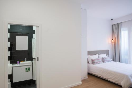 Habitación blanca con cama y espejo en Porto Bonjardim Apartments, en Oporto