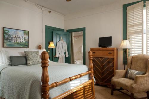 a bedroom with a bed and a chair at St. Francis Inn - Saint Augustine in Saint Augustine