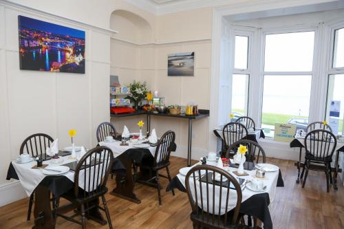 a dining room with tables and chairs and windows at Riviera Guesthouse in Whitby