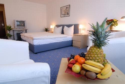 ジンデルフィンゲンにあるHAK ホテル アム クロスターゼーのベッド2台、テーブル(フルーツ付)が備わる客室です。