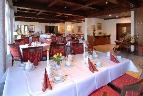 a dining room with a white table and red chairs at HAK Hotel am Klostersee in Sindelfingen