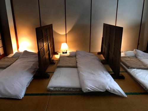 a room with three beds with white sheets and a lamp at Oyado Matsubaya in Minakami