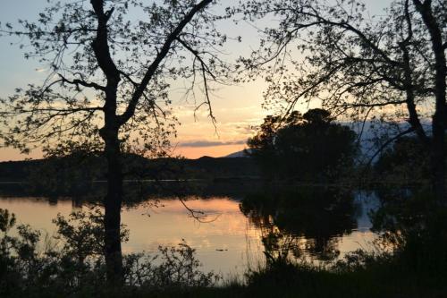 a sunset over a lake with trees in the foreground at Casa Rural Luna in Candeleda