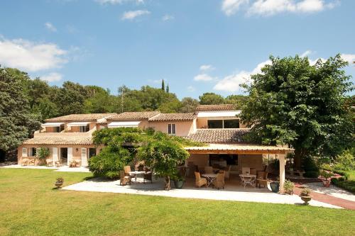a large house with tables and chairs in a yard at Hotel Le Verger Maelvi in Grimaud