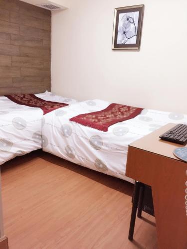 two beds in a room with a desk and a computer at Hong Kong Tai San Guest House (Harilela Branch) in Hong Kong