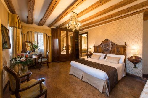 um quarto com uma cama grande, uma mesa e cadeiras em Palazzo Bembo - Exclusive Accommodation em Veneza