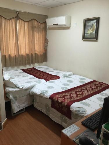 two beds in a small room with a desk at Hong Kong Tai San Guest House (Harilela Branch) in Hong Kong