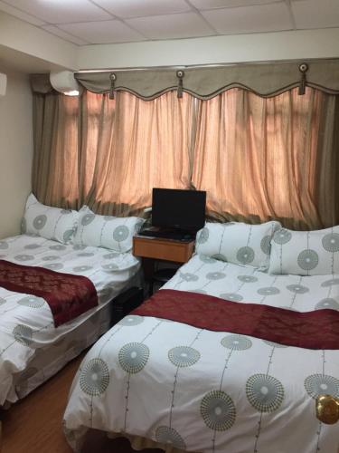 a room with two beds and a laptop on a desk at Hong Kong Tai San Guest House (Harilela Branch) in Hong Kong