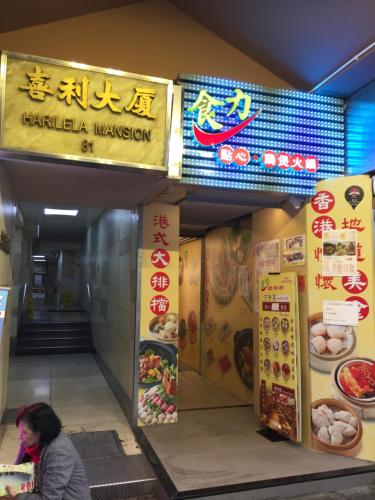 a woman walking in front of a food shop at Hong Kong Tai San Guest House (Harilela Branch) in Hong Kong