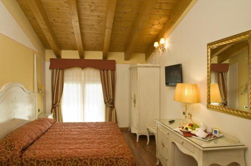 a bedroom with a bed and a dresser and a mirror at Hotel La Campagnola 1926 in Zevio