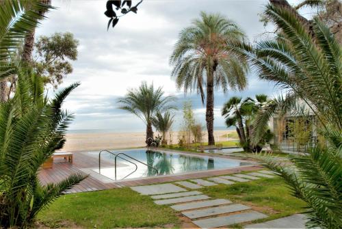 a swimming pool with palm trees and a beach at Botaniq Hotel Boutique in Mojácar