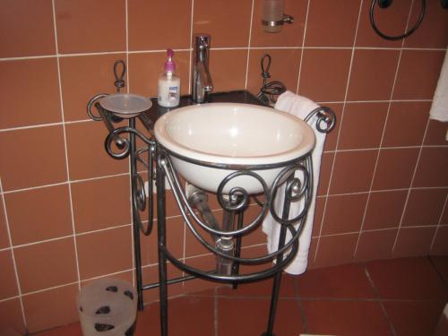 a bathroom with a sink in a tiled wall at Black Swan Guesthouse in Maseru
