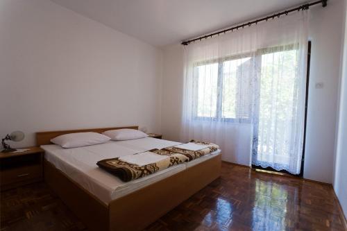 a bedroom with a bed and a large window at Apartments Katić in Vantačići