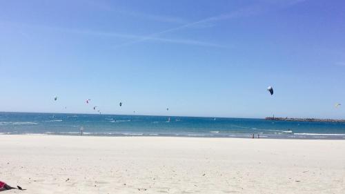 a group of people on a beach flying kites at Viana do Castelo, Cabedelo Beach Apartment in Viana do Castelo