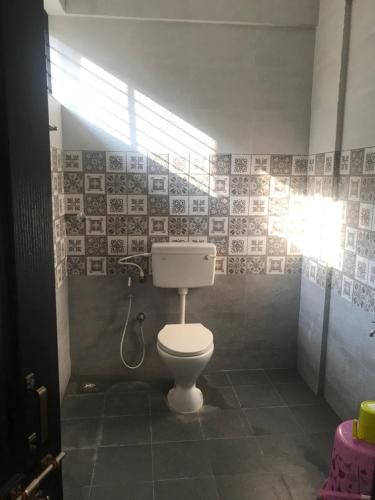 a bathroom with a white toilet in a room at SUPREME LODGe in Dharmastala