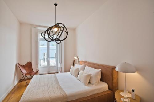 Schlafzimmer mit einem Bett, einem Fenster und einer Lampe in der Unterkunft Libest Chiado 4 - Alecrim in Lissabon