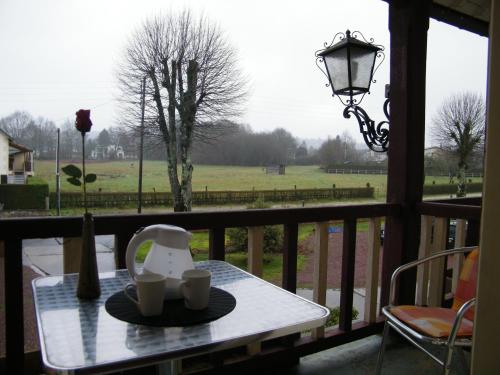 a table on a balcony with a view of a field at Hôtel de Tessé in Bagnoles de l'Orne