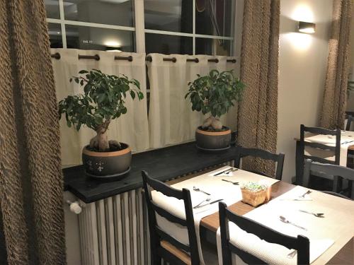 a table in a restaurant with two potted plants at Hotel de la Jamagne & Spa in Gérardmer