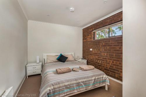 a bedroom with a bed with a brick wall at Bay Retreat Port Arthur in Port Arthur