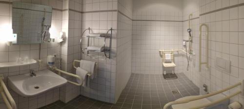 a white tiled bathroom with a sink and a toilet at Hotel Sedes in Berlin