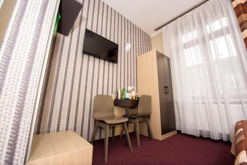 クラクフにあるHotel Kazimierz IIのテーブルと椅子、テレビが備わるホテルルームです。