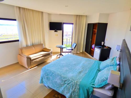 a bedroom with a bed and a couch and a chair at De La Costa Hotel in Encarnación