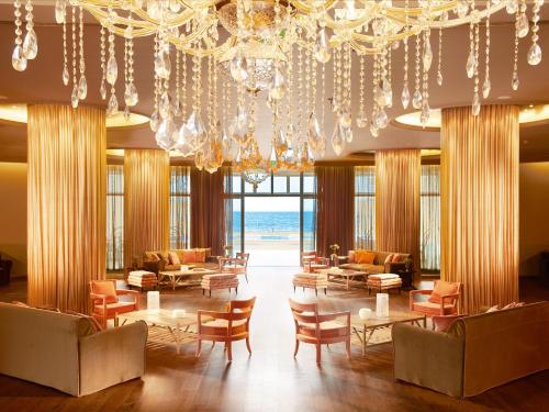 a lobby with chairs and tables and a chandelier at Grecotel Astir Palace in Alexandroupoli