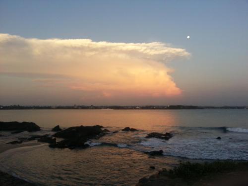 a sunset over a body of water with rocks at Old Parkland Hostel in Galle