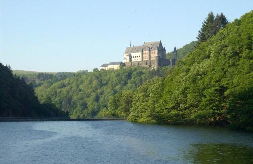 a castle on top of a hill next to a lake at Camping de L'Our Appartements in Vianden