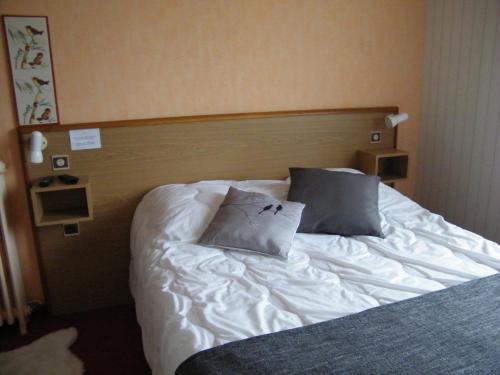 a bed with two pillows on it in a room at Hôtel de Tessé in Bagnoles de l'Orne
