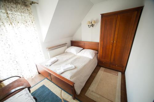 a small bedroom with a bed and a wooden cabinet at Hotel & Spa Arkadia in Tomaszów Lubelski