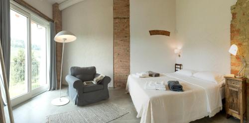 a bedroom with a bed and a chair and a window at Casa Visette in Monforte dʼAlba