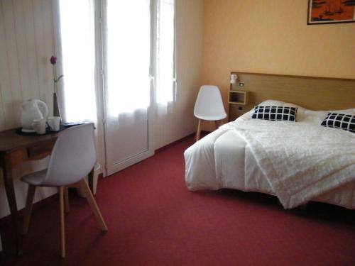 a bedroom with a bed and a table and chairs at Hôtel de Tessé in Bagnoles de l'Orne