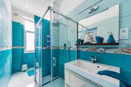 uma casa de banho azul com um lavatório e uma cabina de duche em vidro. em A43 Apartment em Budapeste