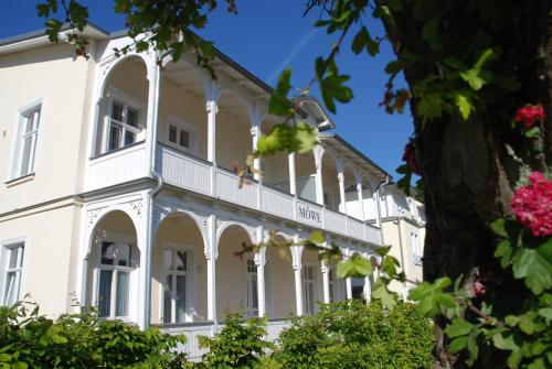 ein weißes Gebäude mit einem Balkon und Blumen in der Unterkunft Haus Möwe - Apt. 05 in Ostseebad Sellin