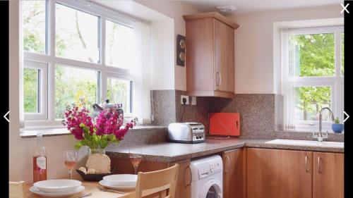 a kitchen with a table with flowers on it at Yr Hafan in Trelech