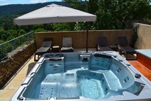 a hot tub on a patio with an umbrella at Hôtel Le Colombier in Moustiers-Sainte-Marie