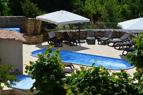 a pool with chairs and umbrellas in a yard at Hôtel Le Colombier in Moustiers-Sainte-Marie