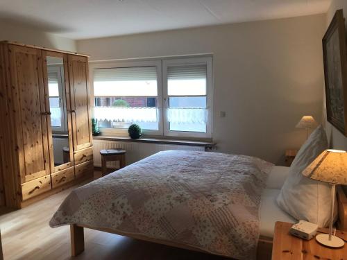 a bedroom with a bed and two windows at Ferienwohnung Hage in Hage