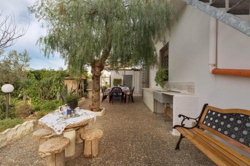 Un patio con una mesa y bancos y un árbol. en Appartamenti delle rose by BarbarHouse, en Torre Lapillo